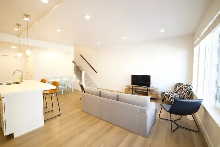Open-concept living area featuring wood-finish flooring, recessed lighting, and large windows