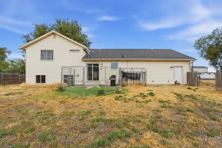 Rear exterior featuring a sliding glass door, a privacy fence, and a dedicated outdoor space with chain-link fencing
