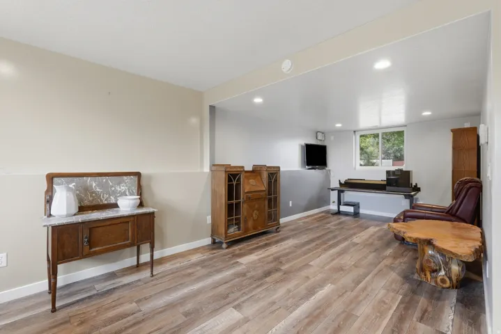 Spacious room featuring wood-finish flooring, recessed lighting, a window with natural light, and two-tone wall paint
