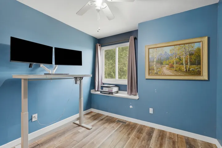 Room featuring wood-finish flooring, a ceiling fan, and a window with a white sill