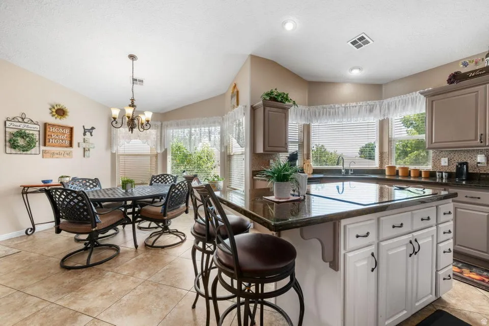 Kitchen with a central island featuring a dark stone countertop and white cabinetry