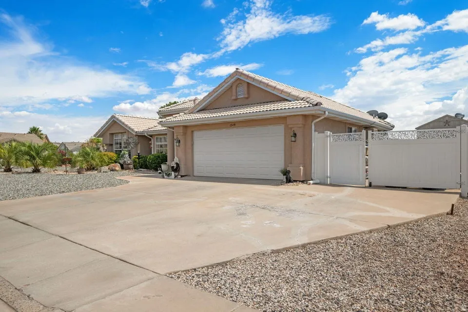 Exterior featuring a two-car garage, concrete driveway, and white privacy gates