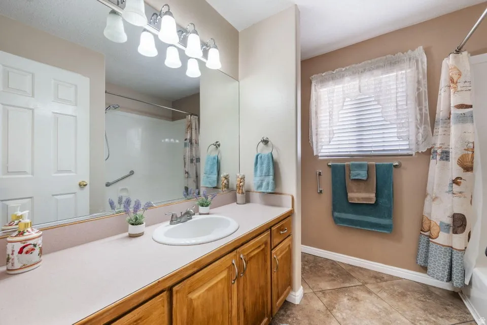 Bathroom featuring a light-toned vanity countertop with an integrated sink, wood-finish cabinetry, and a vanity mirror with overhead lighting