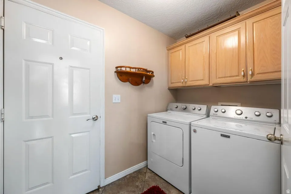 Dedicated laundry area featuring light wood-finish cabinetry, a white paneled door, and neutral-toned walls