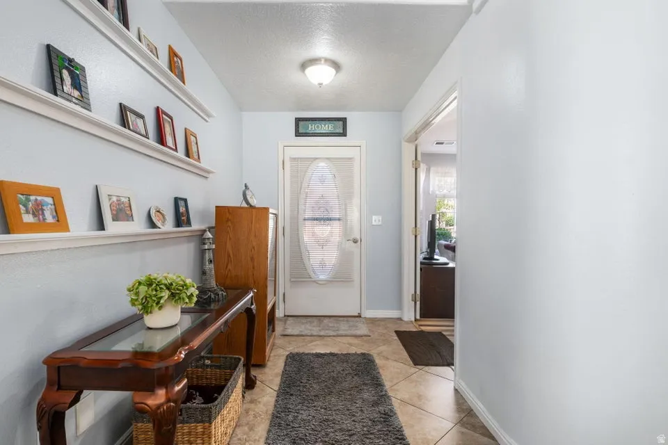 Entryway featuring light blue walls, ceramic tile flooring, a decorative front door with an oval glass insert, and a flush-mount ceiling light