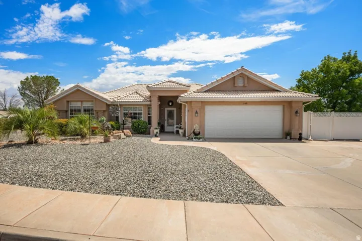 Single-story stucco residence with a tiled roof, integrated two-car garage, and a concrete driveway