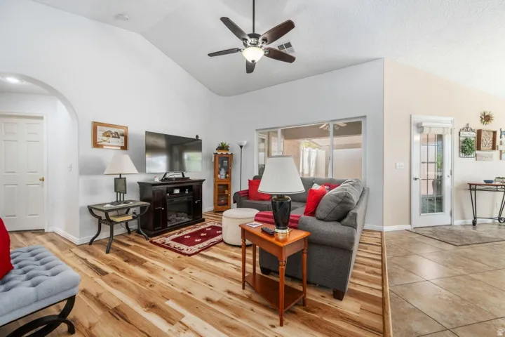 Spacious living area featuring wood-finish flooring, vaulted ceilings, and a ceiling fan