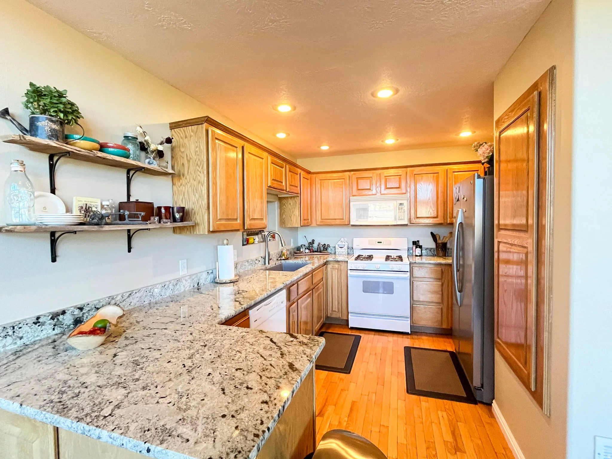 Kitchen featuring light wood cabinetry and light-toned granite-style countertops
