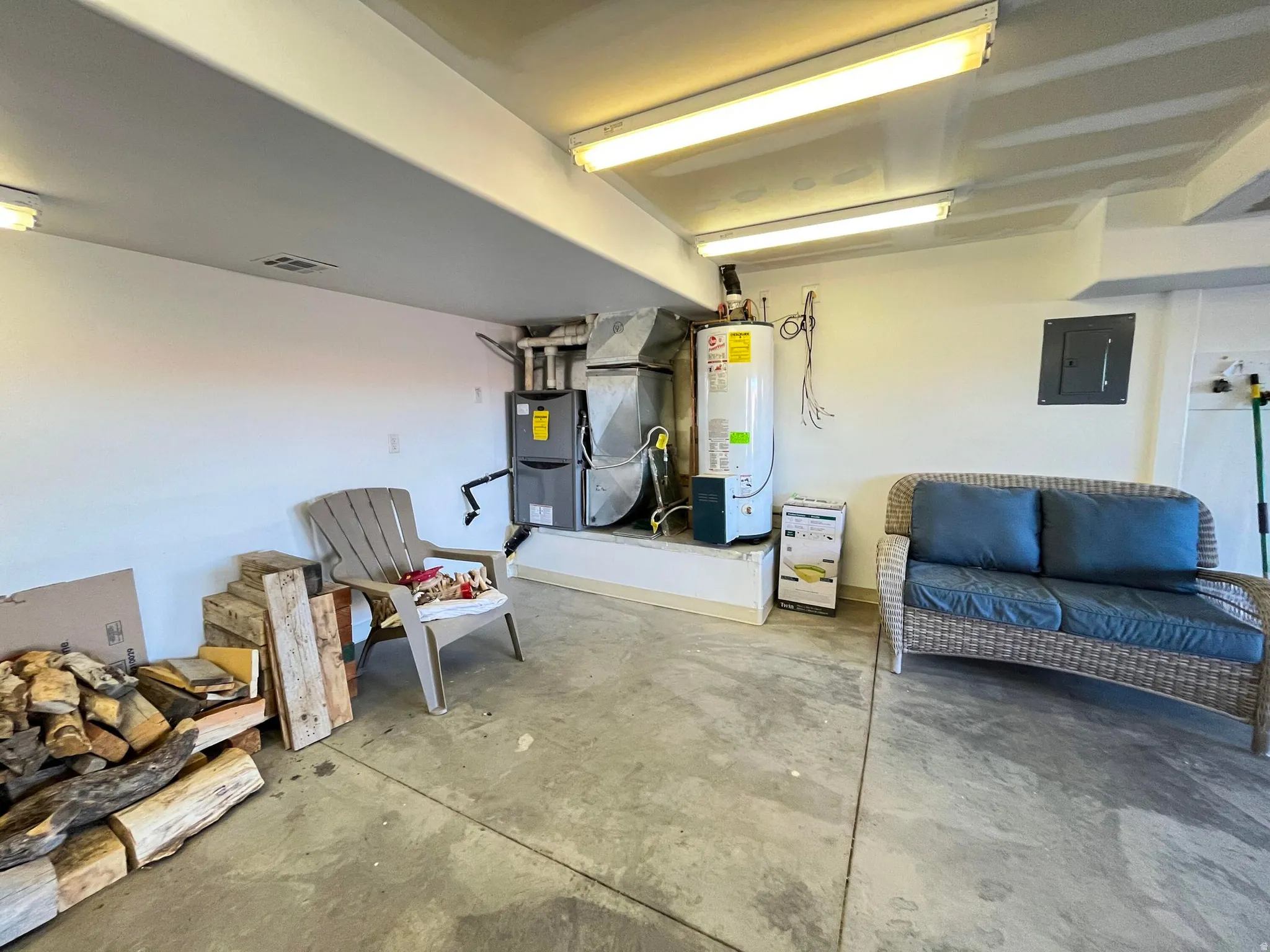 Concrete flooring in a utility space featuring a water heater and HVAC system