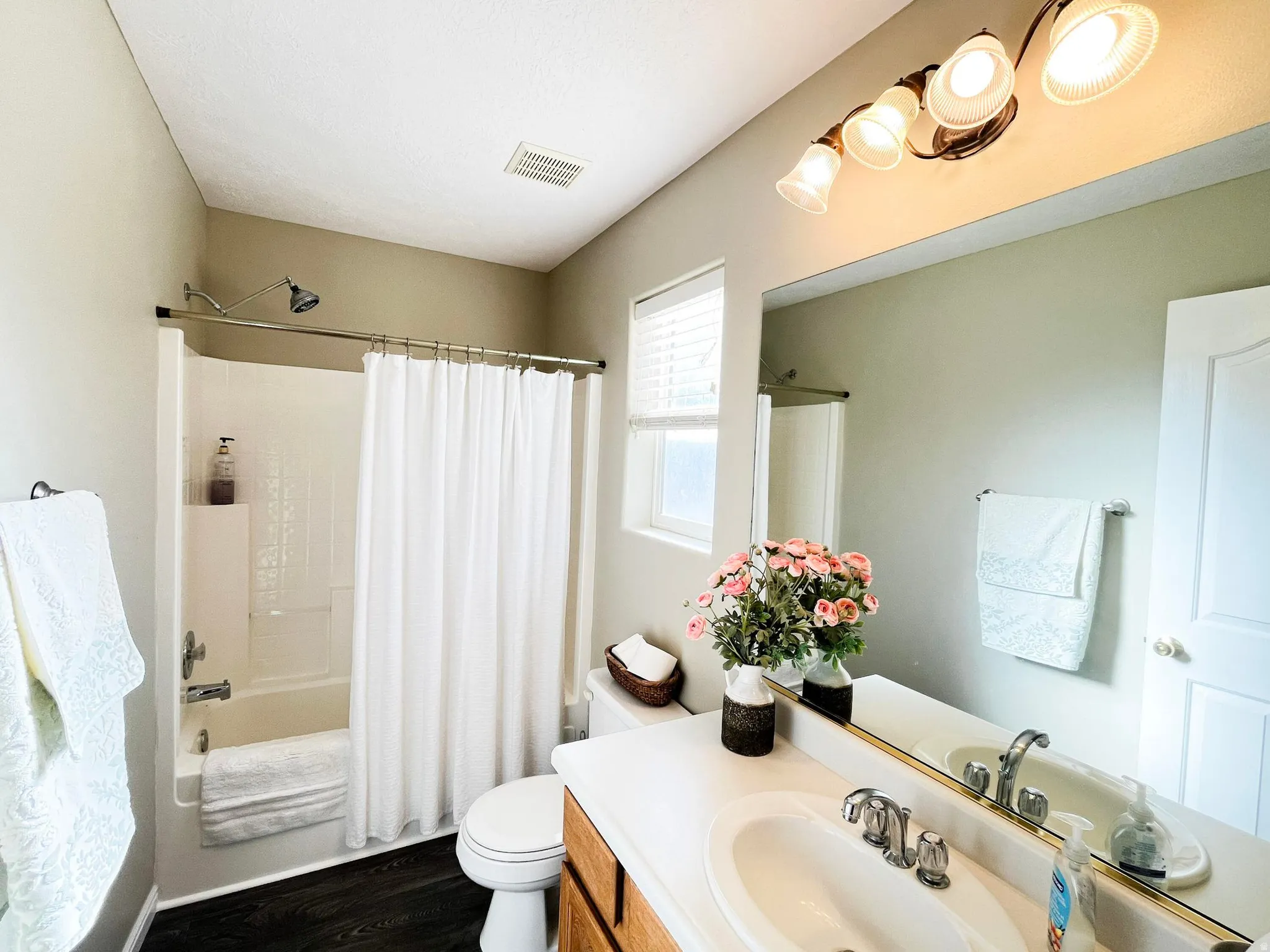 Full bathroom featuring a white tub/shower combination, white toilet, and dark wood-finish flooring