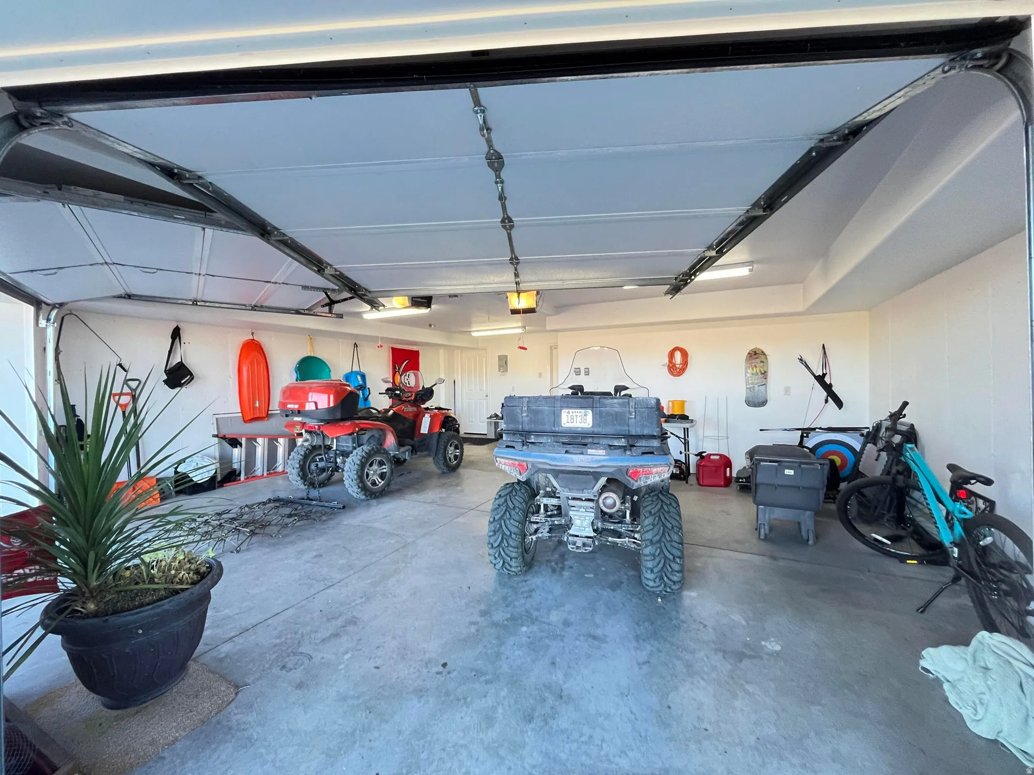 Spacious garage with an open overhead door, featuring concrete flooring and interior wall paneling