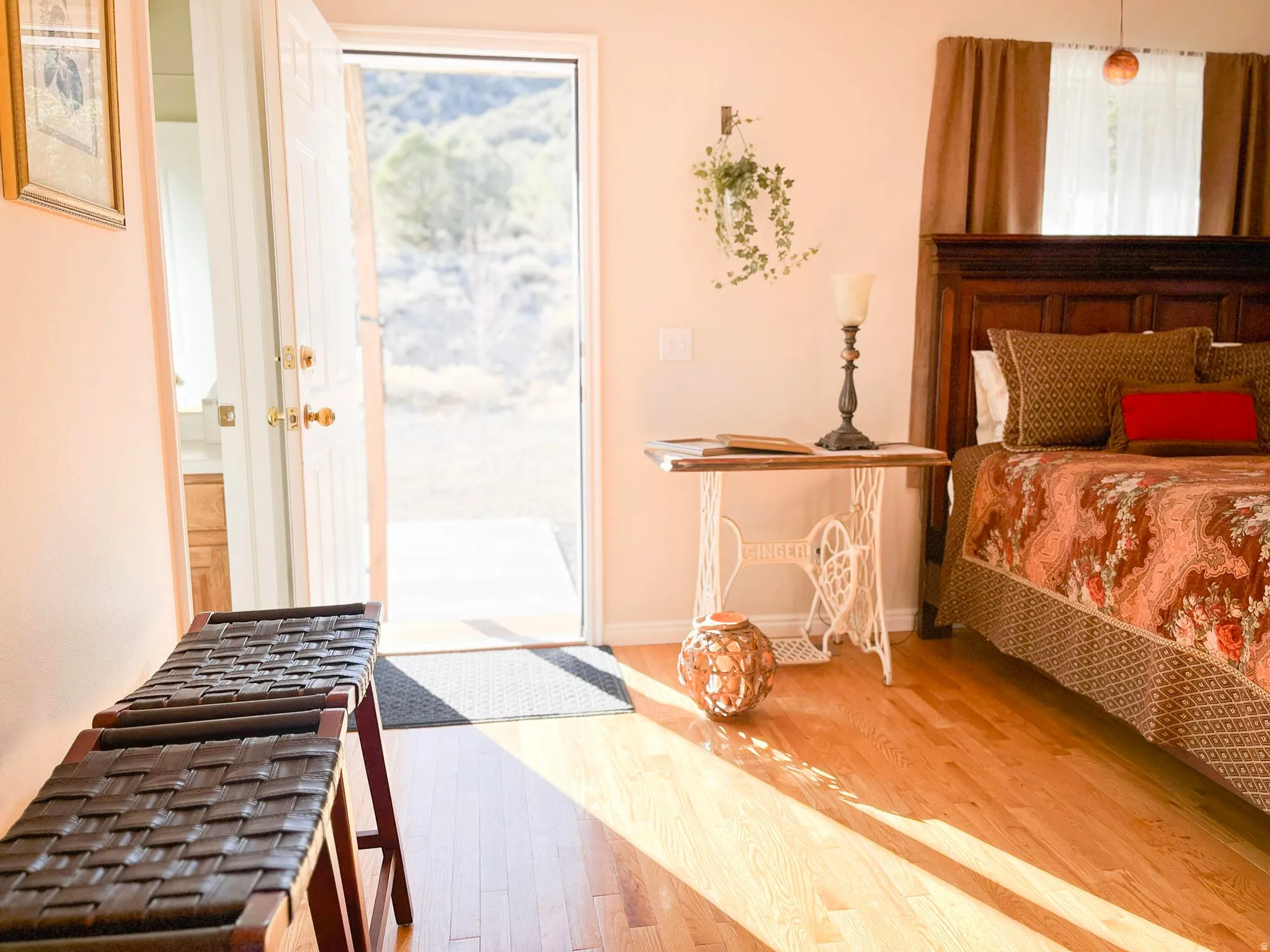 Hardwood flooring throughout featuring an exterior door with brass hardware, a dark wood headboard, and light-toned walls