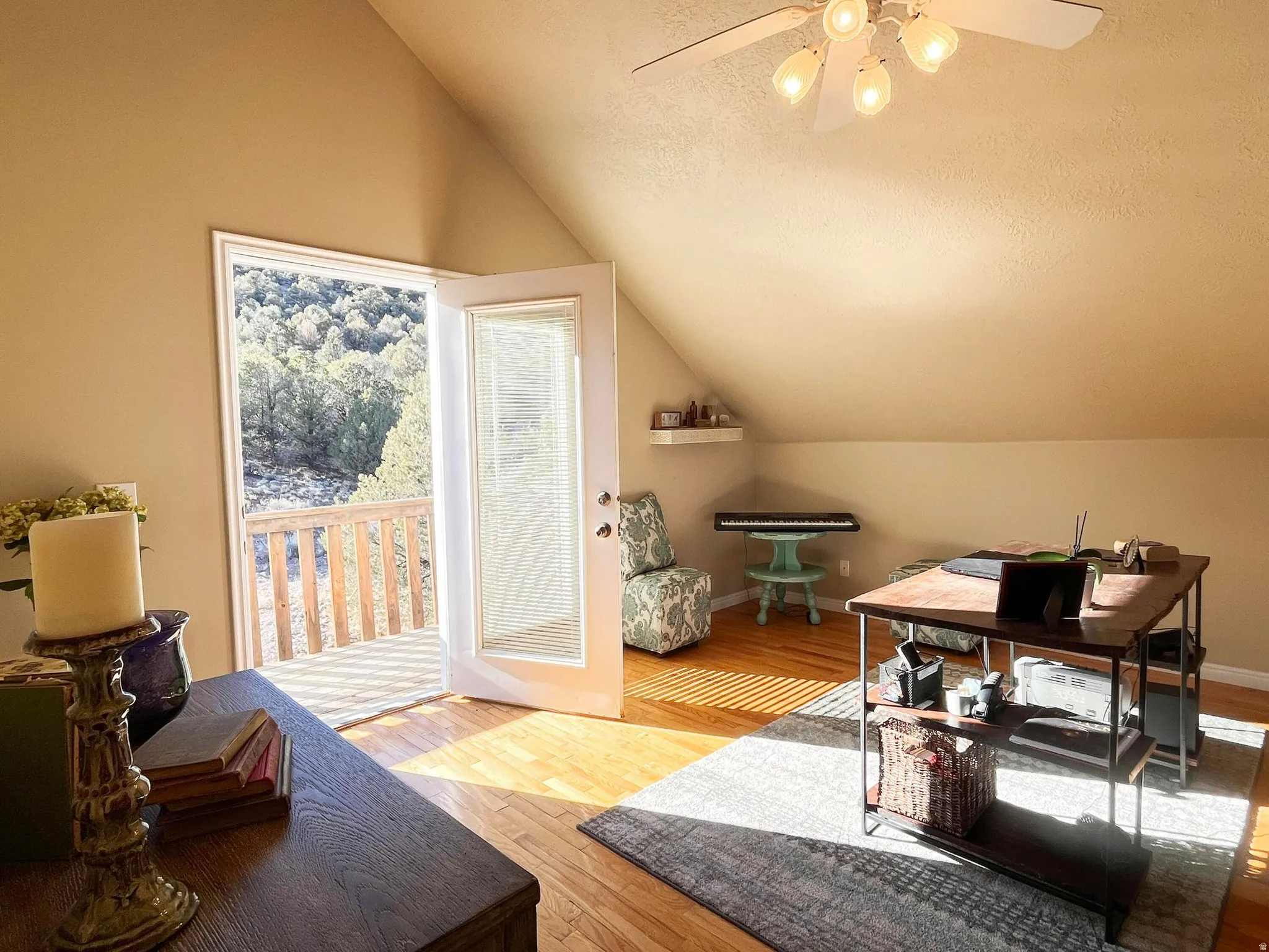 Room featuring wood-finish flooring, a ceiling fan with integrated lighting, and a sloped ceiling design