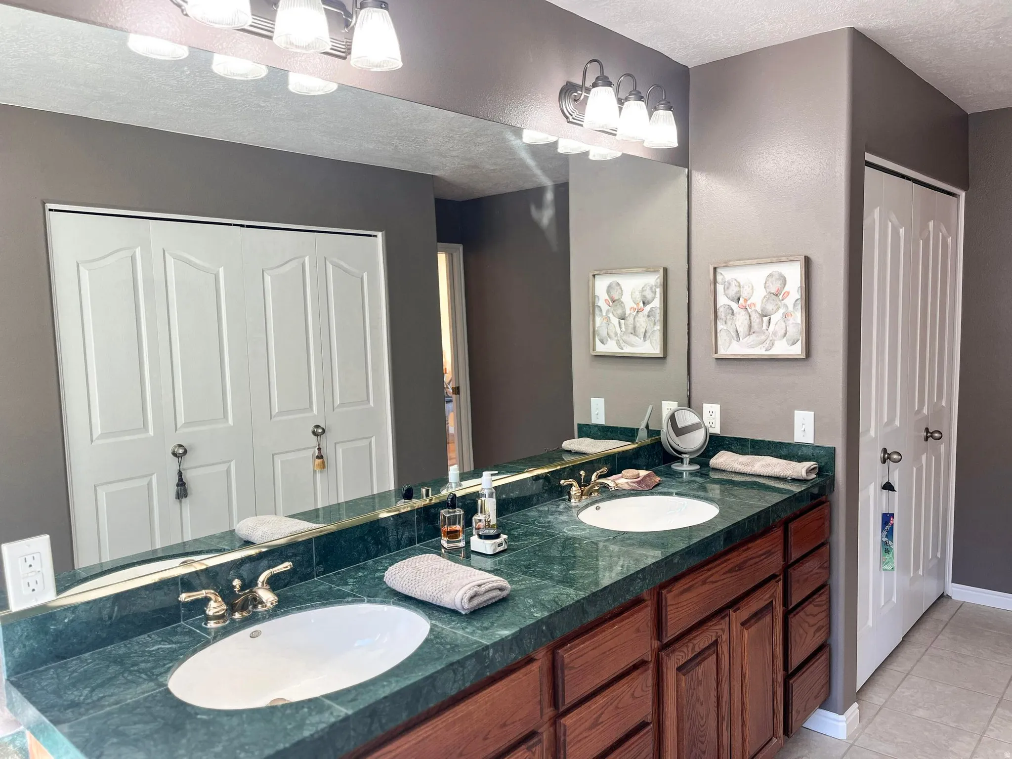 Double vanity featuring a green stone countertop with integrated sinks, brass-finish faucets, and wood cabinetry