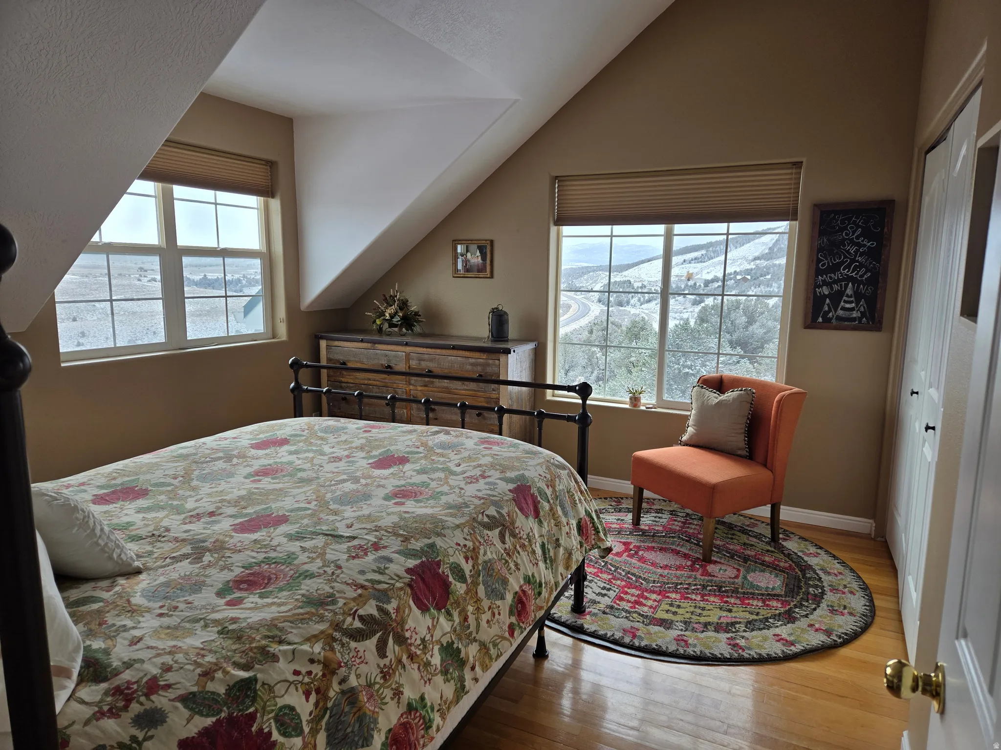 Room featuring multiple windows with cellular shades, hardwood flooring, an angled ceiling, and a built-in closet with bi-fold doors