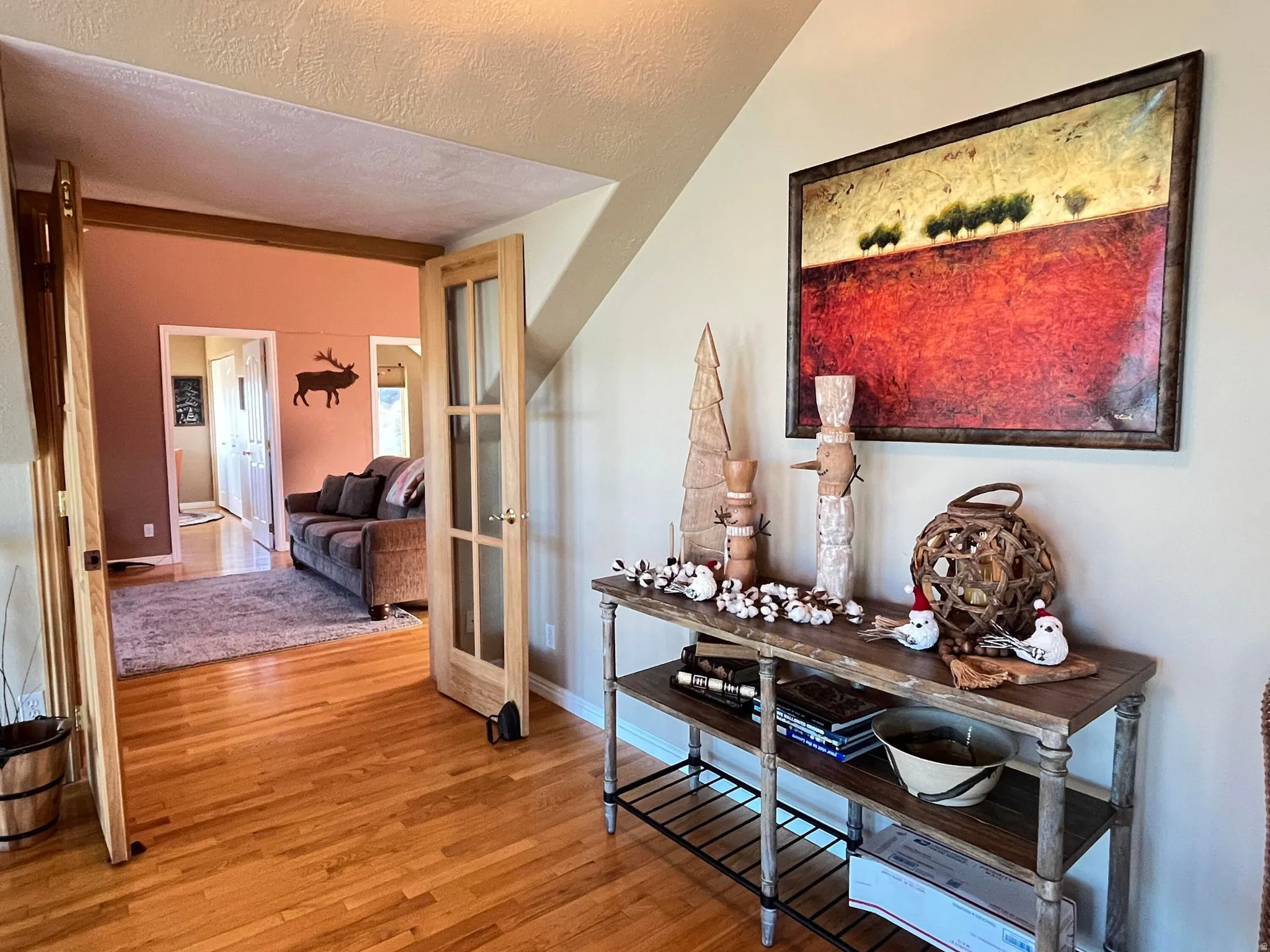 Wood-finish flooring extends through an entryway featuring French doors with clear glass panes