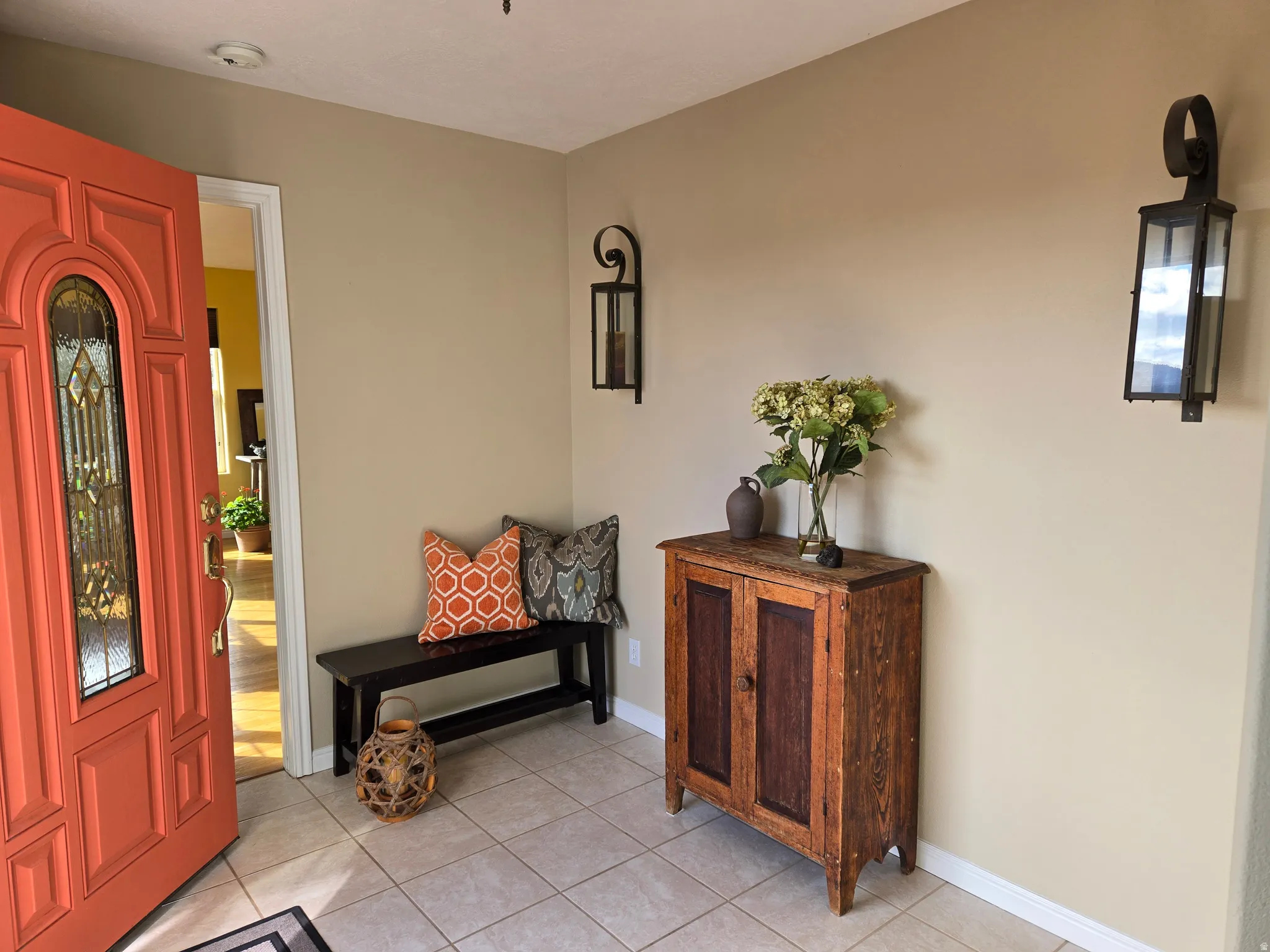 Inviting entryway featuring a paneled entry door with decorative glass inlay, neutral wall tones, and tiled flooring