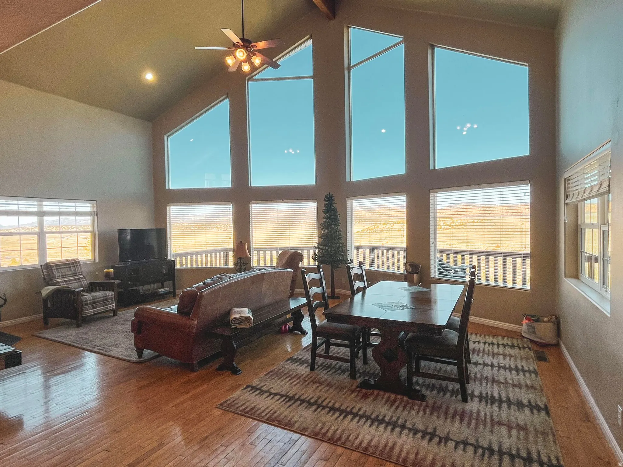 Vaulted ceiling featuring a ceiling fan, recessed lighting, and multiple large windows with horizontal blinds