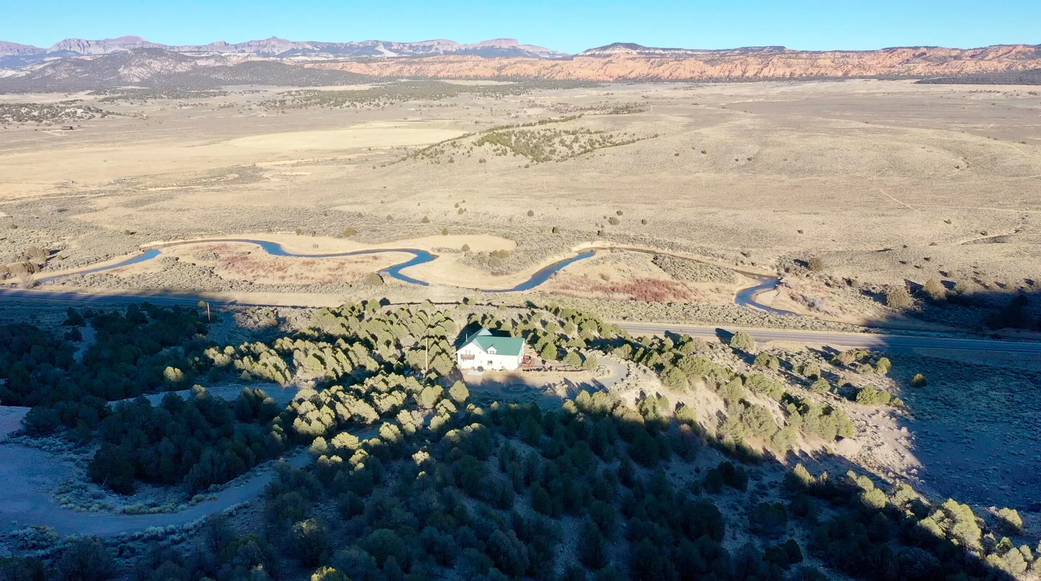 White residence with a green roof, set among natural desert landscaping