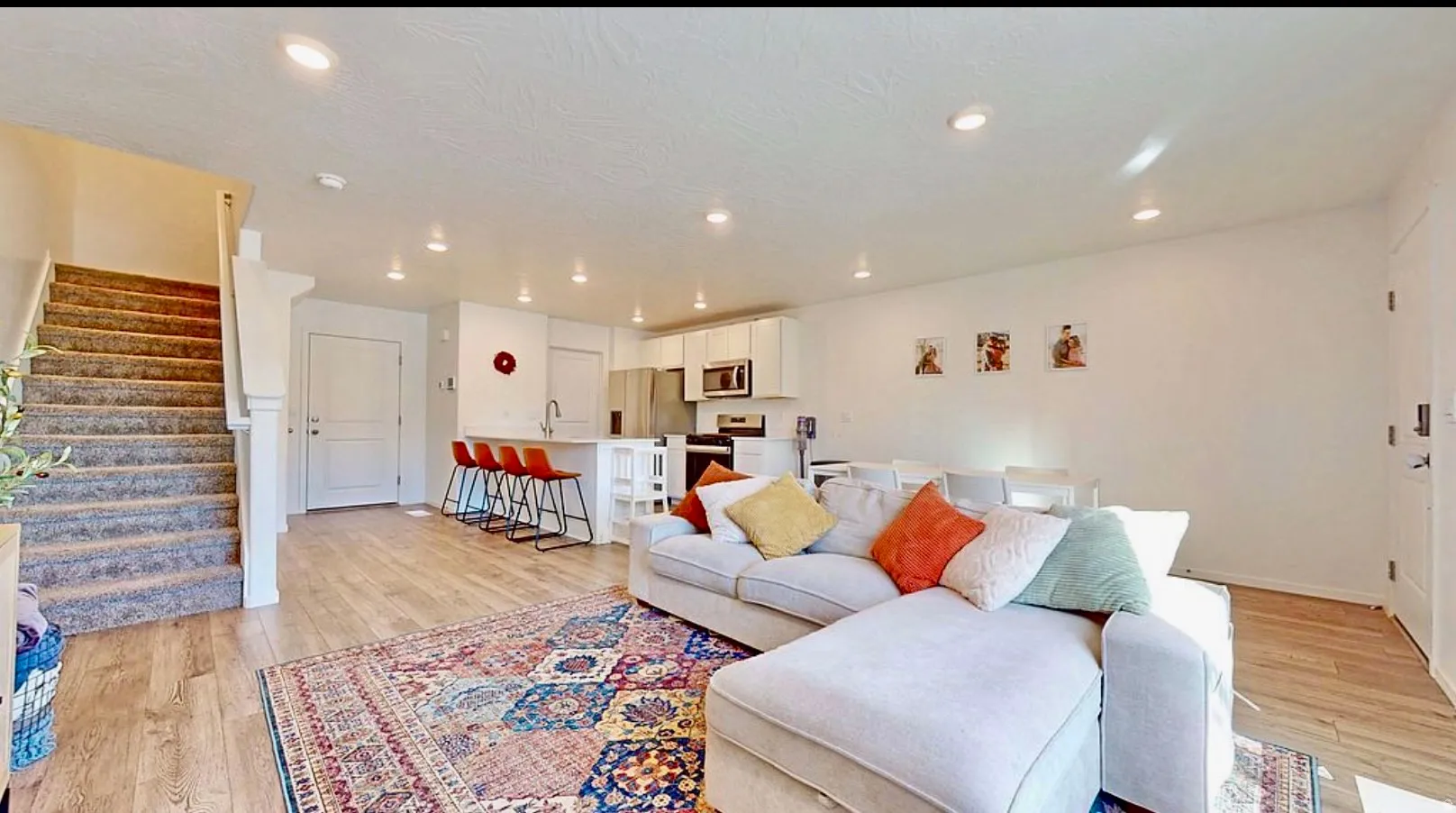 Spacious open-concept living area featuring wood-finish flooring, recessed lighting, and a white interior door