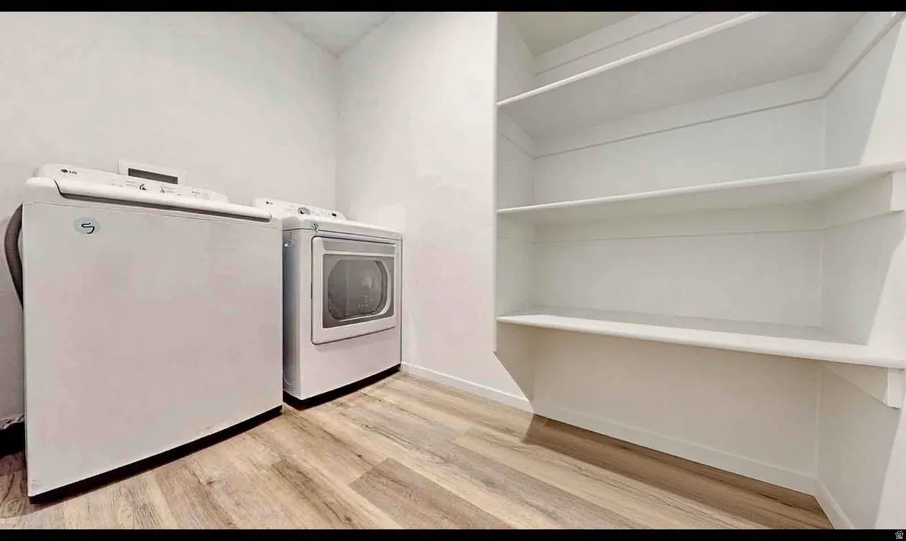 Laundry area featuring wood-finish flooring and extensive built-in shelving