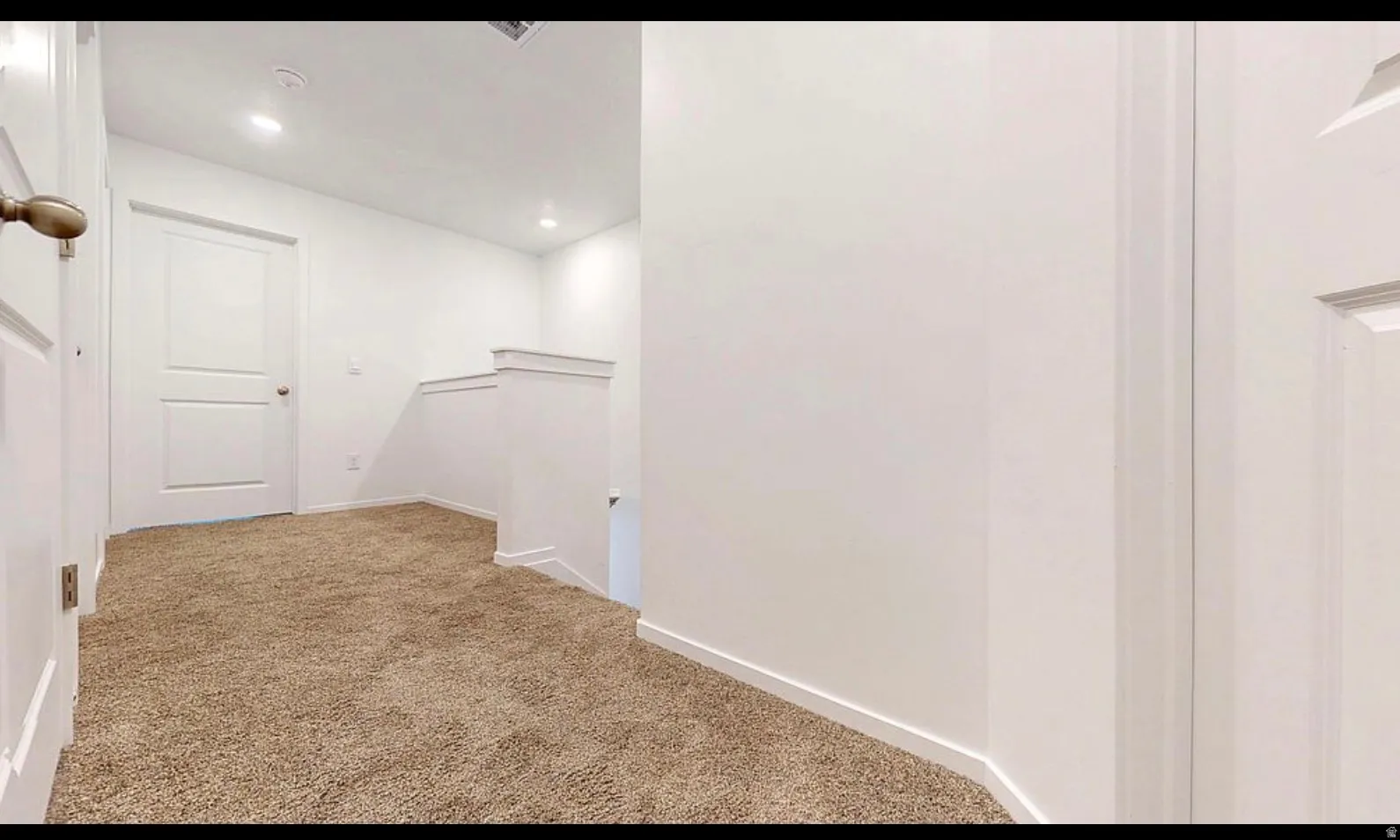 Carpeted hallway featuring white walls, recessed lighting, and white paneled doors with bronze-finish hardware