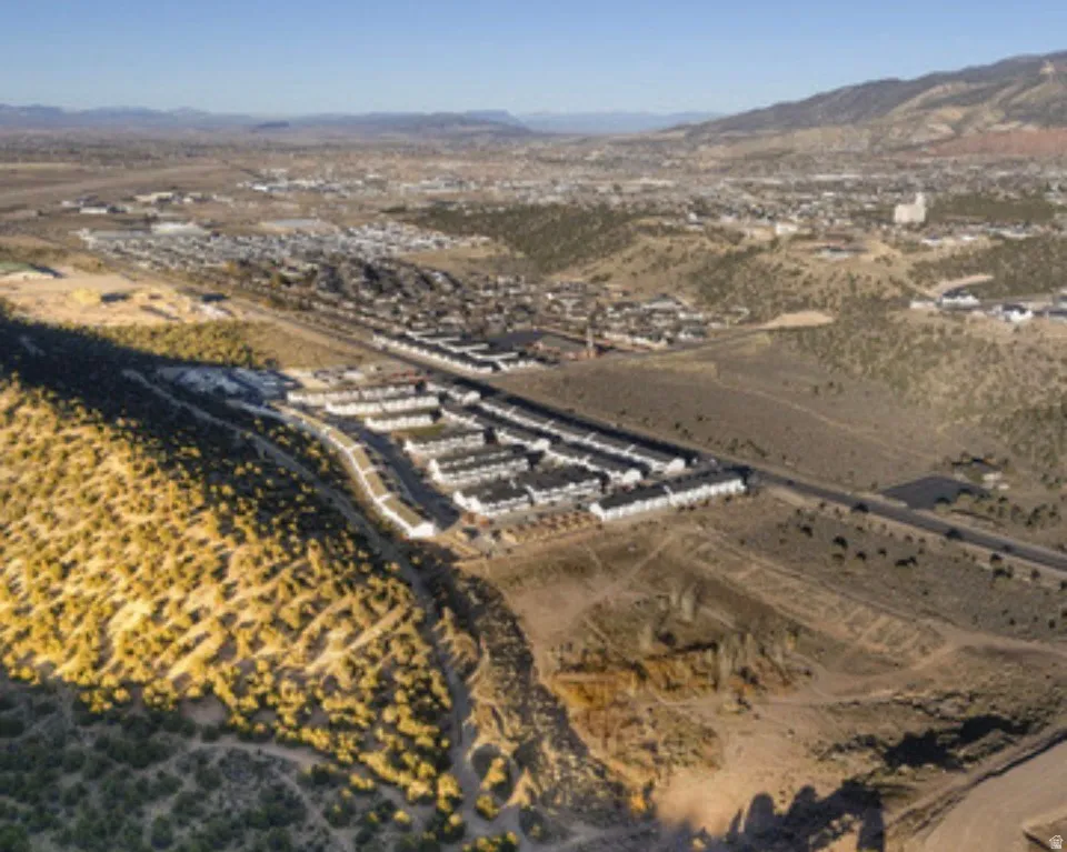 Aerial perspective showcasing a residential development with structured rows of townhomes, surrounded by arid landscape and distant mountains