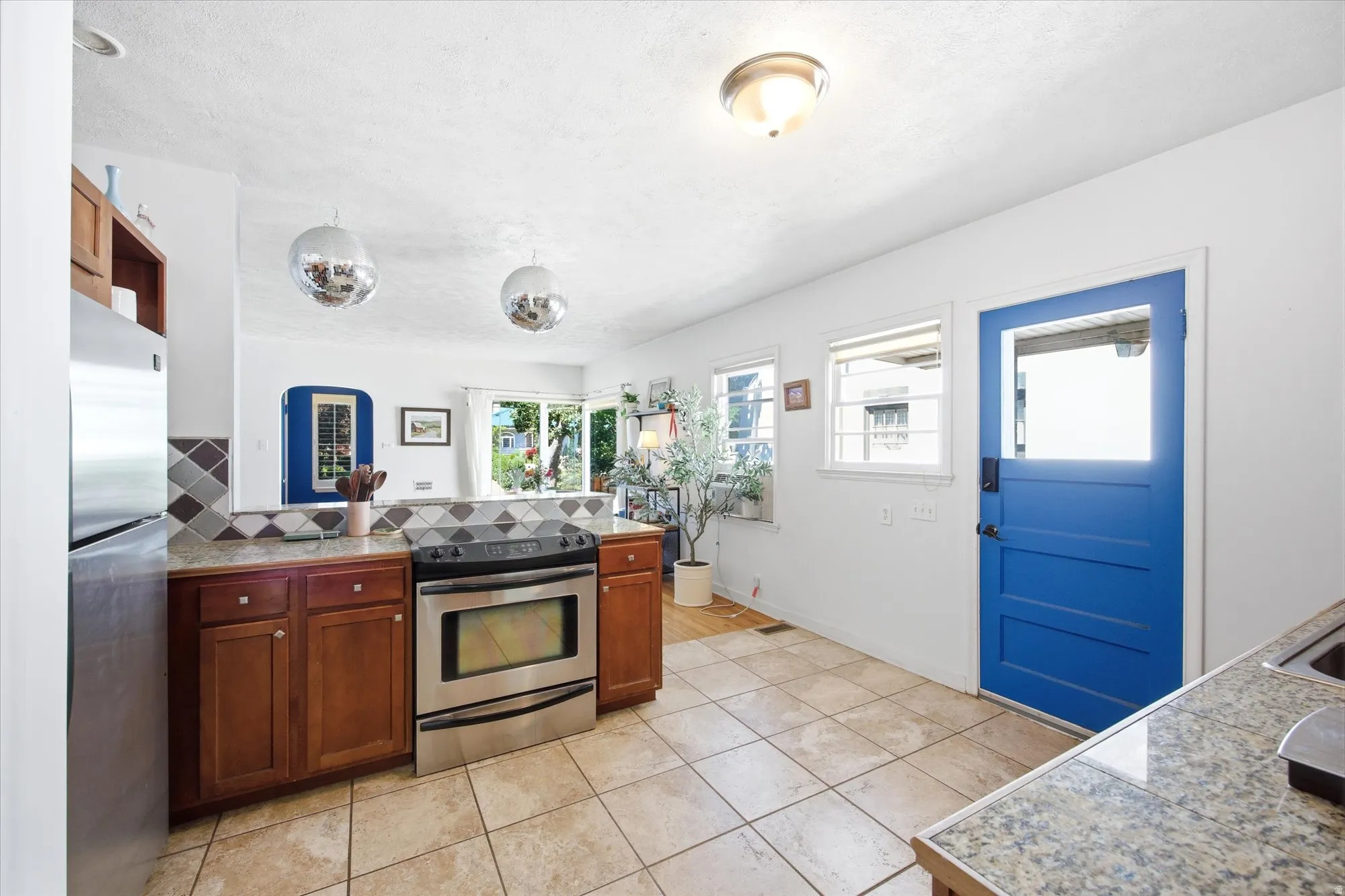 Kitchen featuring tile flooring, stainless steel range, wood cabinetry, stone countertops, and a blue paneled door