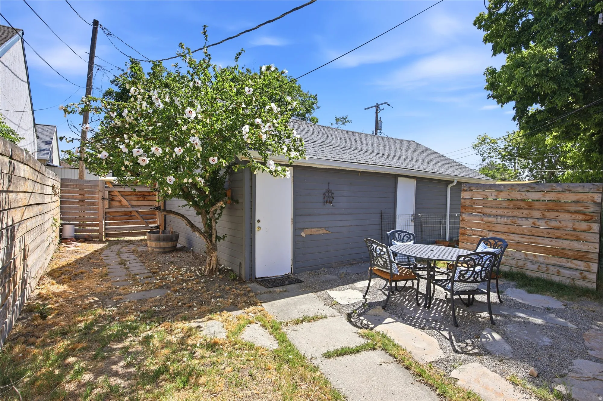 Private outdoor patio area featuring flagstone pavers, a flowering tree, and horizontal wood fencing