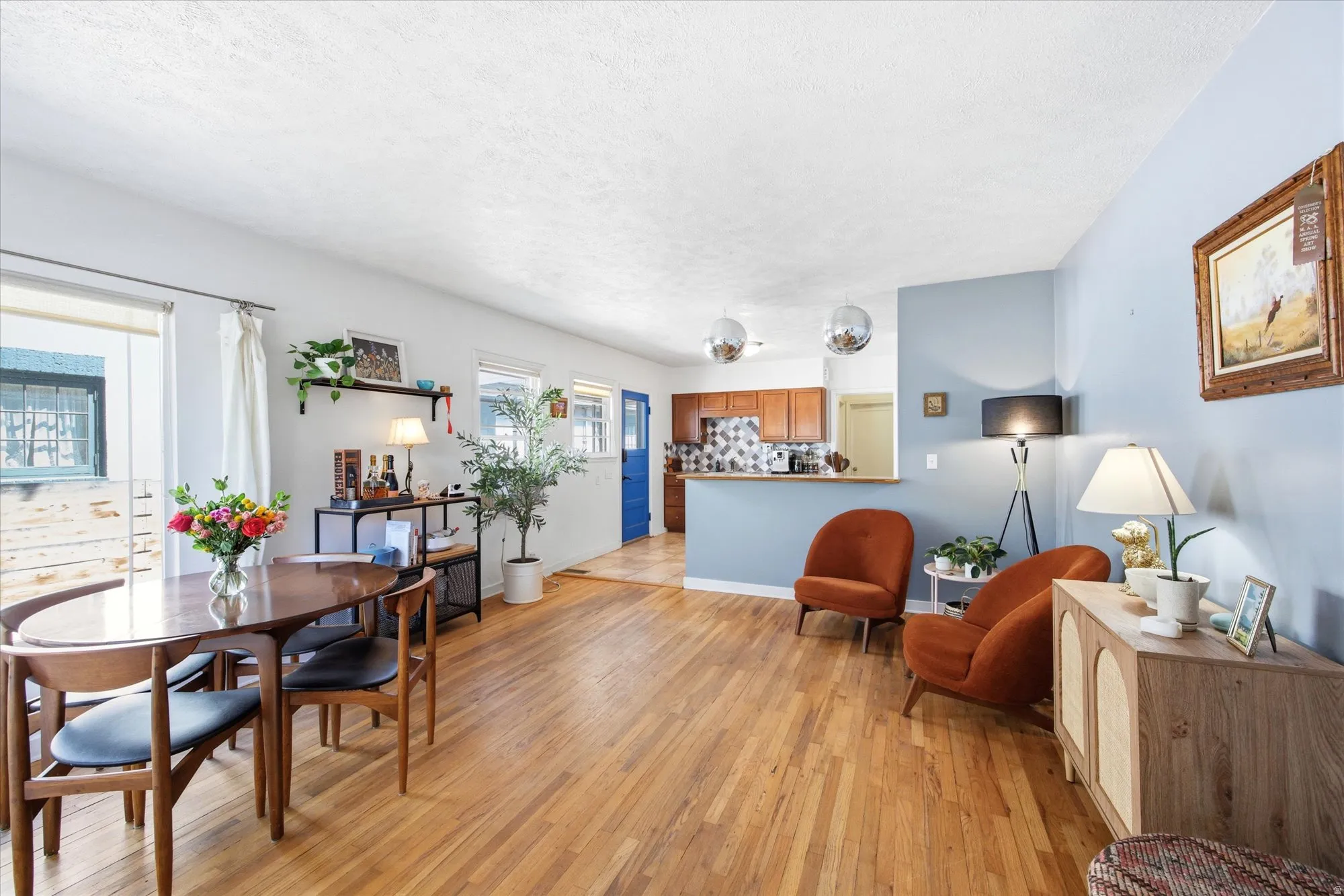 Open-concept living area featuring wood-finish flooring, white walls, and a light blue accent wall