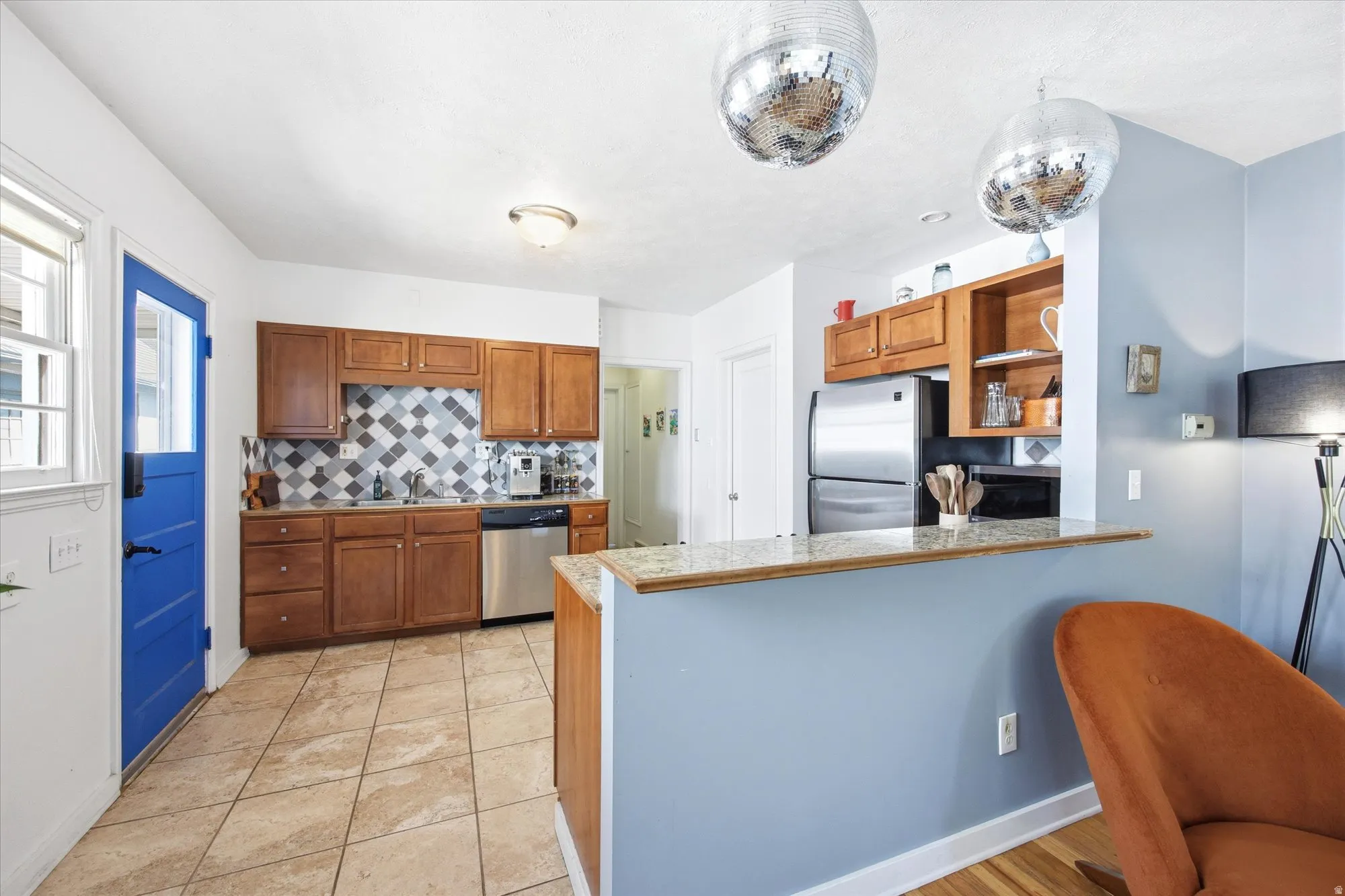 Kitchen featuring wood cabinetry, stainless steel dishwasher, tile backsplash with a geometric pattern, and tiled flooring