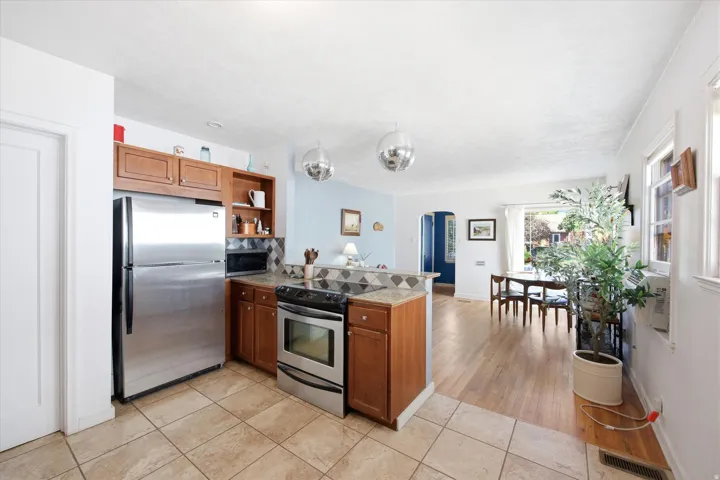 Kitchen featuring stainless steel appliances, wood cabinetry, tiled flooring, and a tiled backsplash
