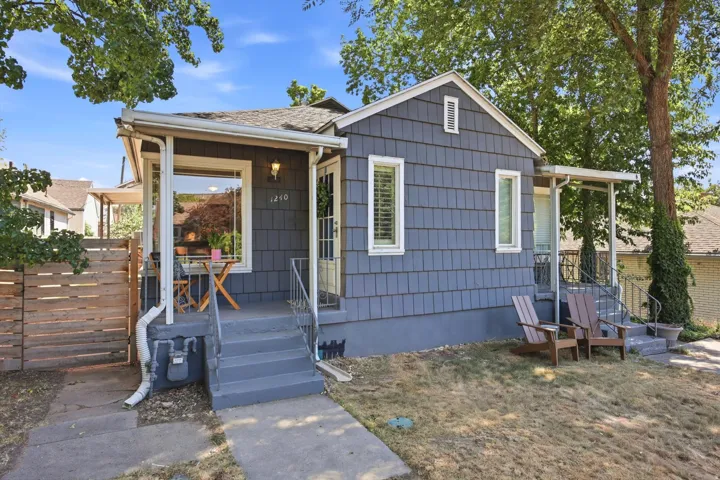 Charming bungalow exterior featuring horizontal plank siding, a covered front porch, and a wooden privacy fence