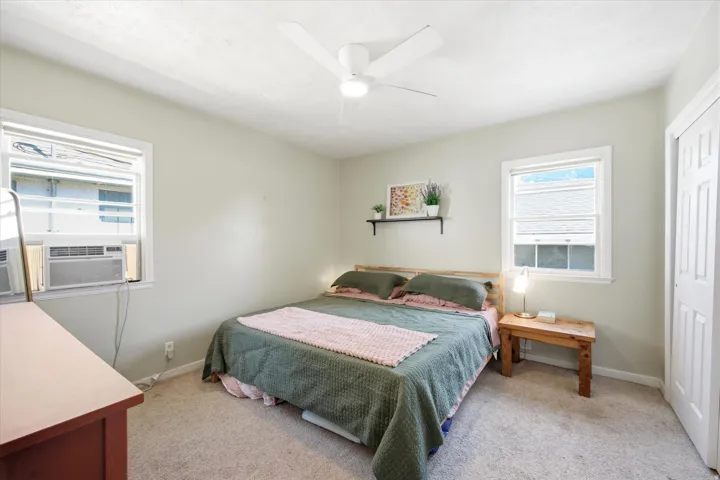 Bedroom featuring two windows, neutral carpet flooring, and a ceiling fan