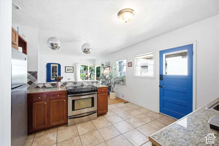 Kitchen featuring tile flooring, stainless steel range, wood cabinetry, stone countertops, and a blue paneled door