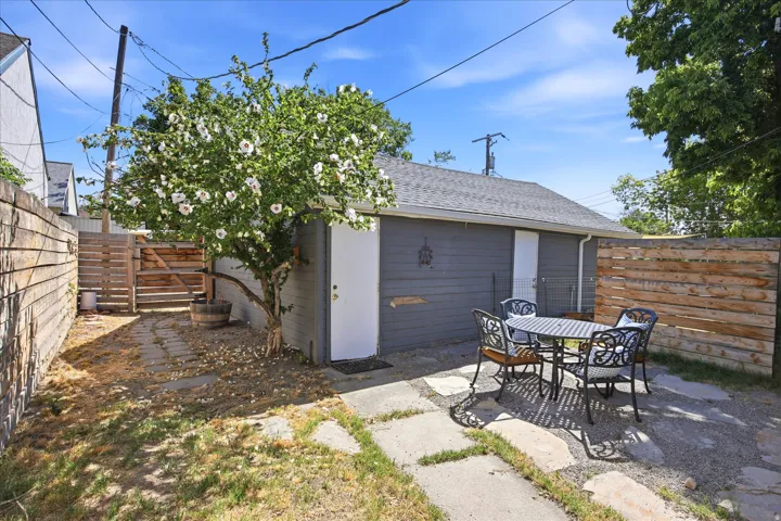 Private outdoor patio area featuring flagstone pavers, a flowering tree, and horizontal wood fencing