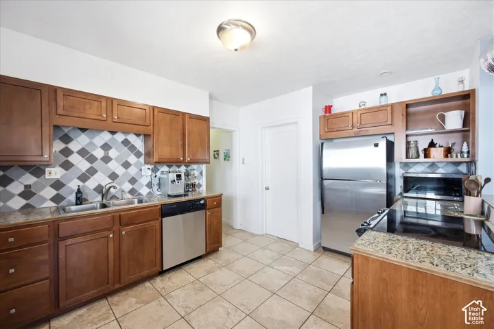 Full kitchen featuring wood cabinetry, stainless steel appliances, and a tiled backsplash with diamond pattern