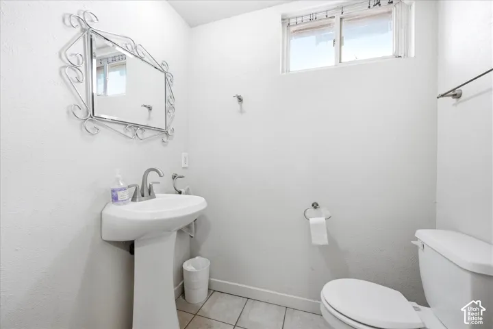 Bathroom featuring a pedestal sink, chrome-finish faucet, and a window providing natural light