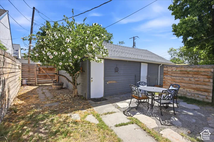 Private outdoor patio area featuring flagstone pavers, a flowering tree, and horizontal wood fencing