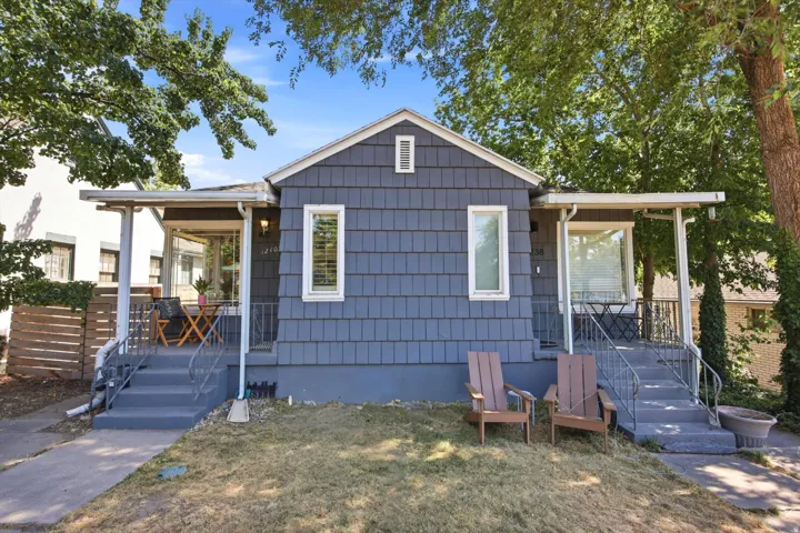 Shingle-sided exterior featuring twin covered porches, white window trim, and established trees