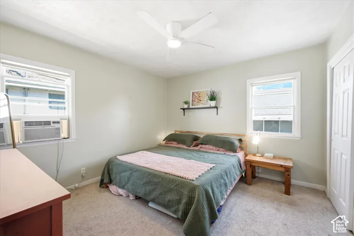 Bedroom featuring two windows, neutral carpet flooring, and a ceiling fan