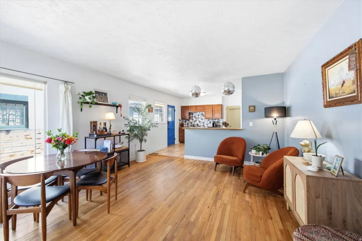 Open-concept living area featuring wood-finish flooring, white walls, and a light blue accent wall