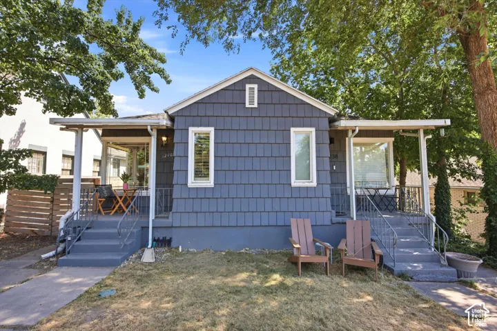 Shingle-sided exterior featuring twin covered porches, white window trim, and established trees