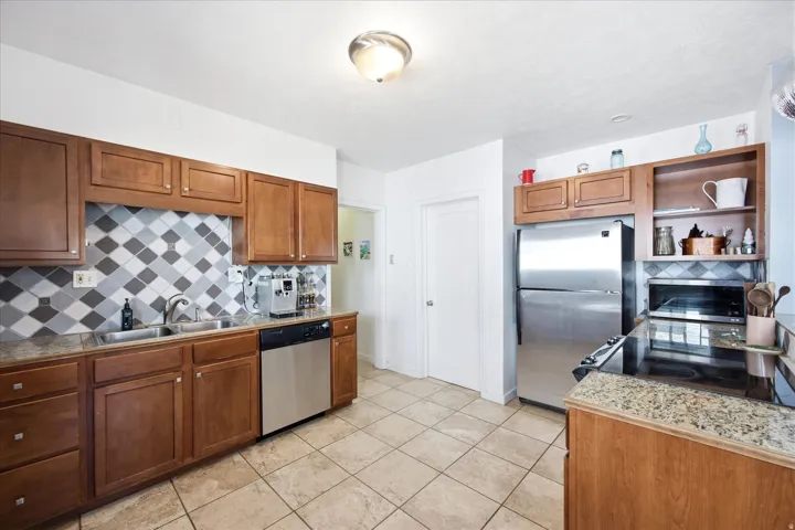 Full kitchen featuring wood cabinetry, stainless steel appliances, and a tiled backsplash with diamond pattern