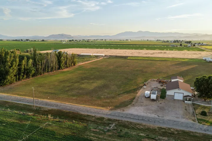 Expansive agricultural property featuring a central field, surrounding cultivated land, and a detached building with a large garage door