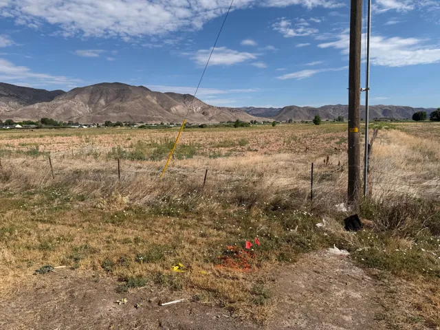 Expansive open land featuring distant mountains, a utility pole, and a wire fence line