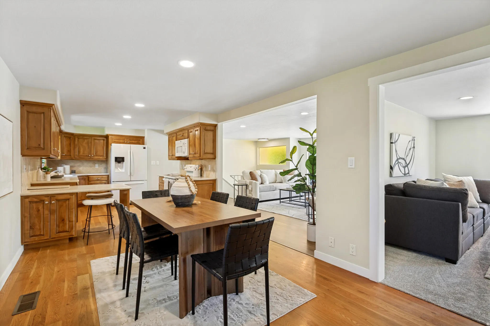 Open-concept kitchen and dining area featuring wood-finish flooring, recessed lighting, wood cabinetry, and a peninsula with seating