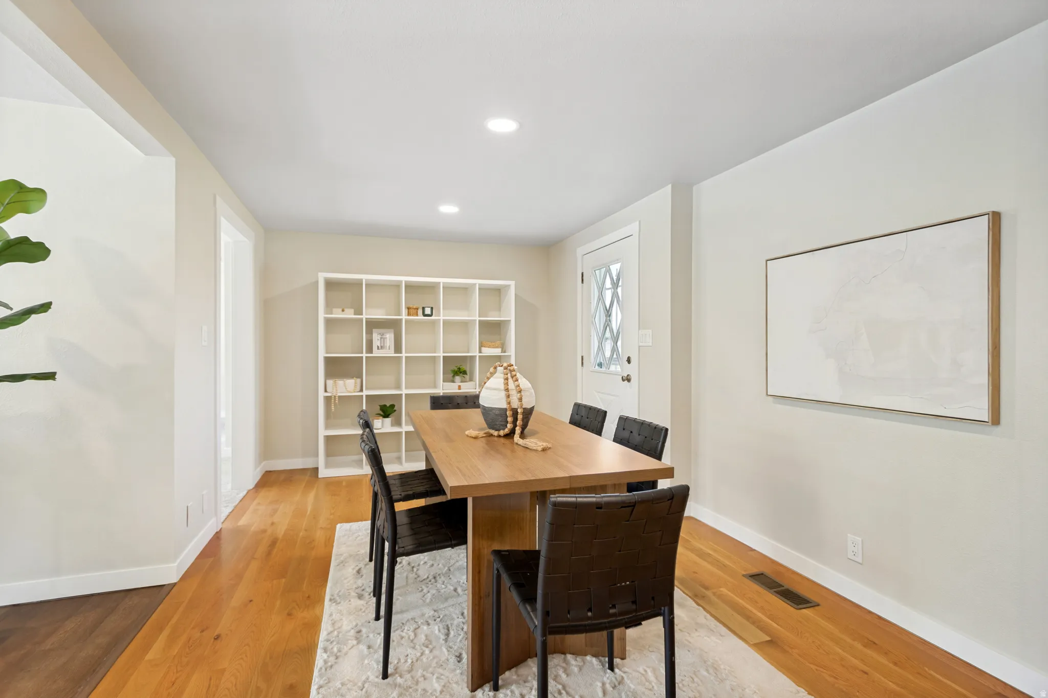 Bright dining area featuring hardwood flooring, recessed lighting, a white built-in shelving unit, and neutral wall tones