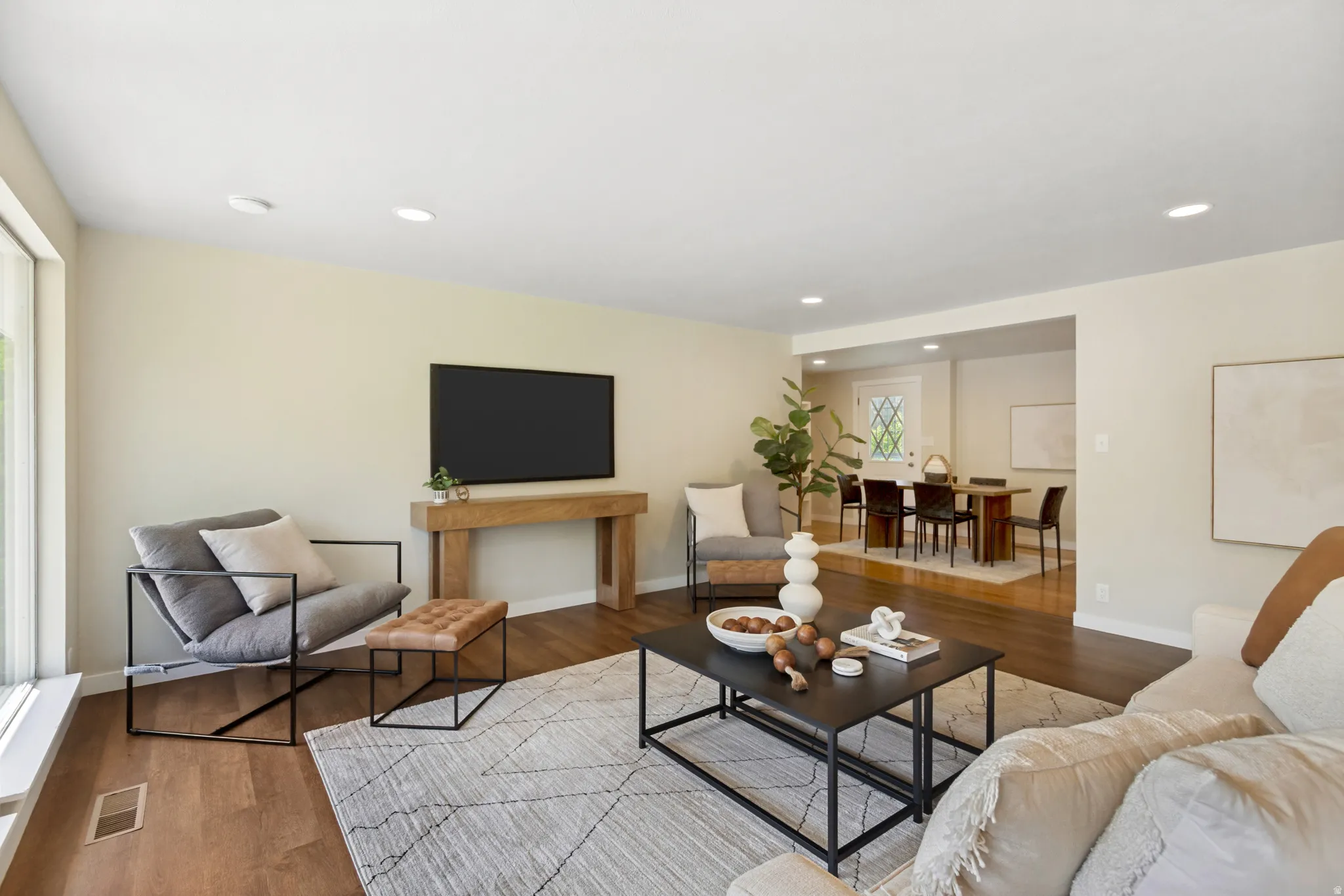 Living area featuring wood-finish flooring, recessed lighting, and ample natural light from large windows