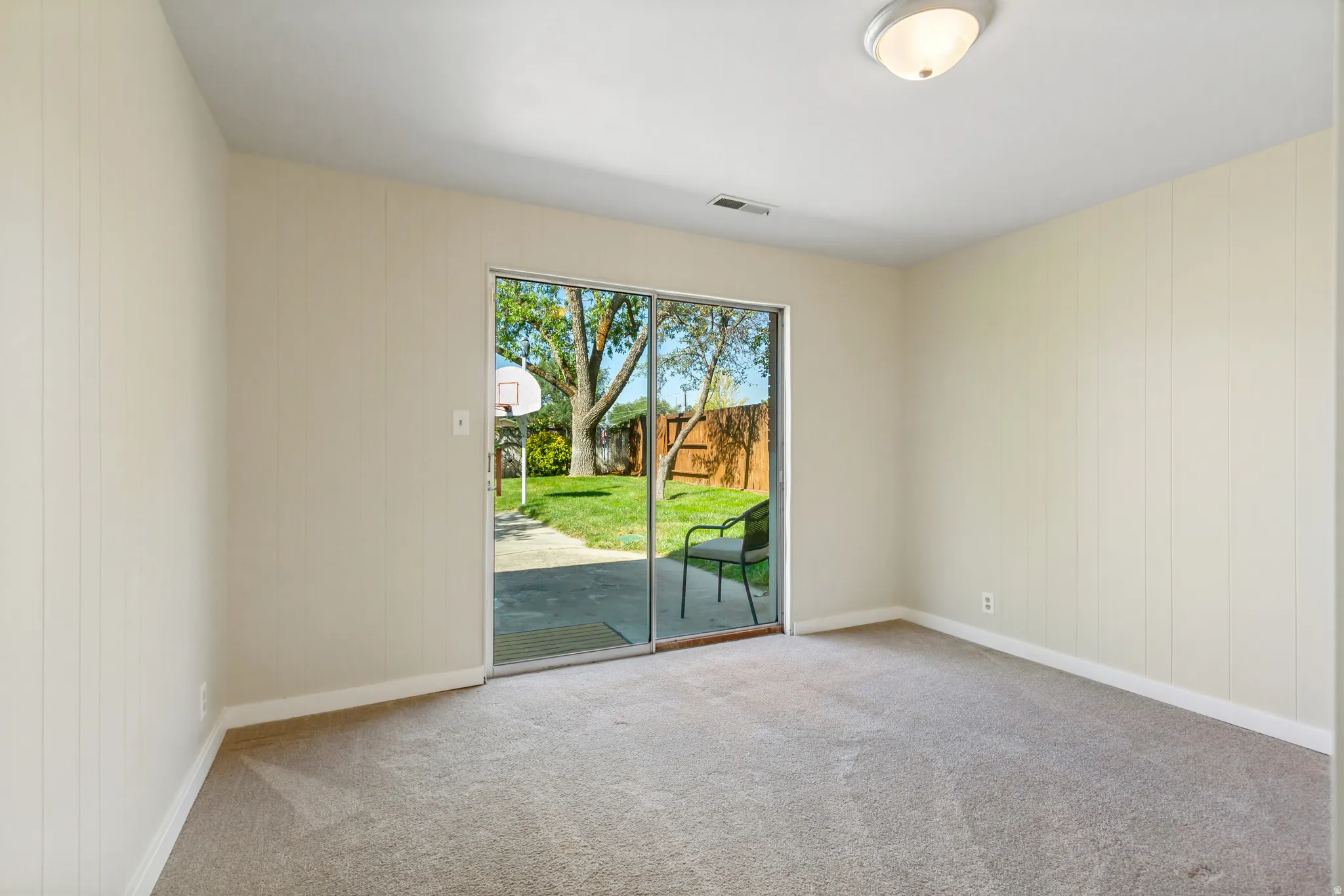 Bedroom #1 in basement with walkout to backyard. Room featuring light beige walls and neutral carpeting